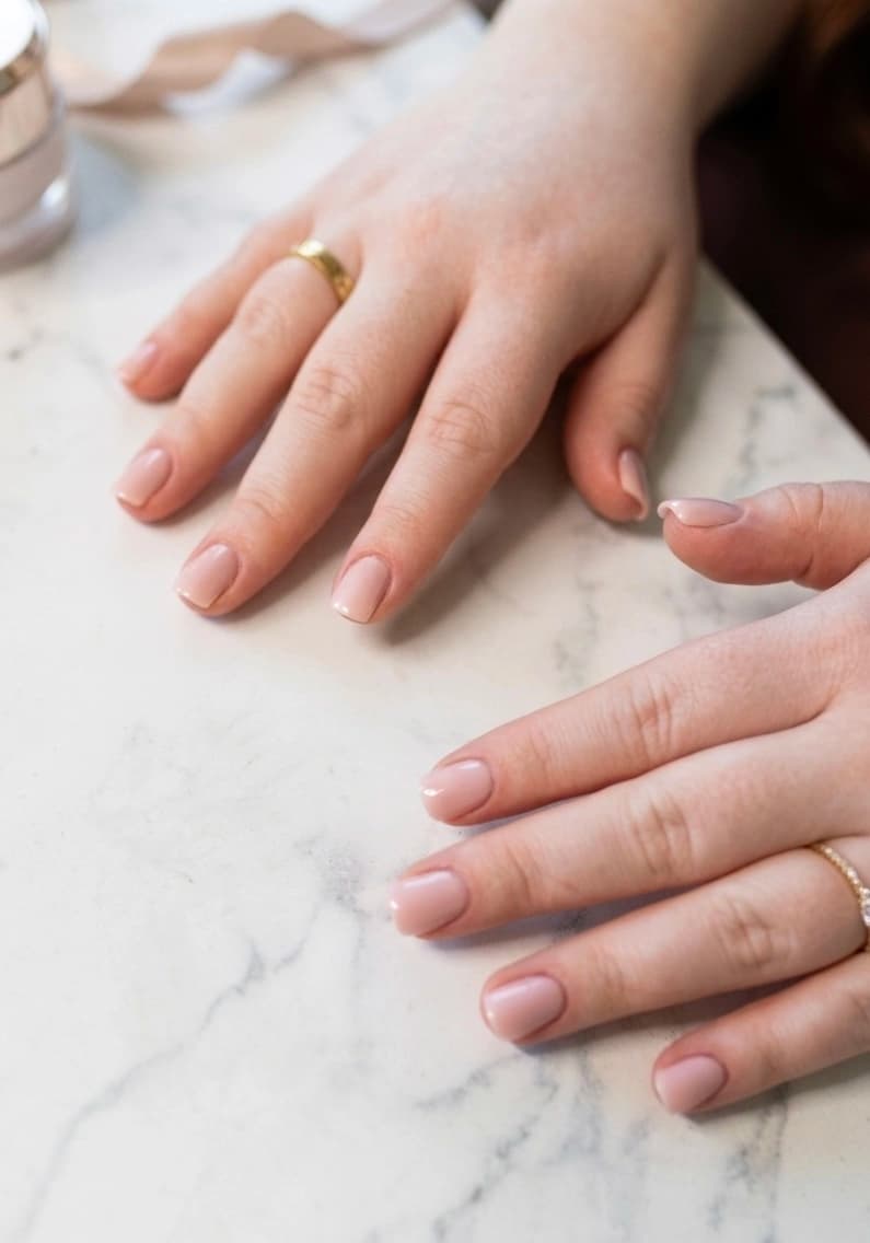 Manucure semi-permanent nude rosée glossy ovale, sur marbre